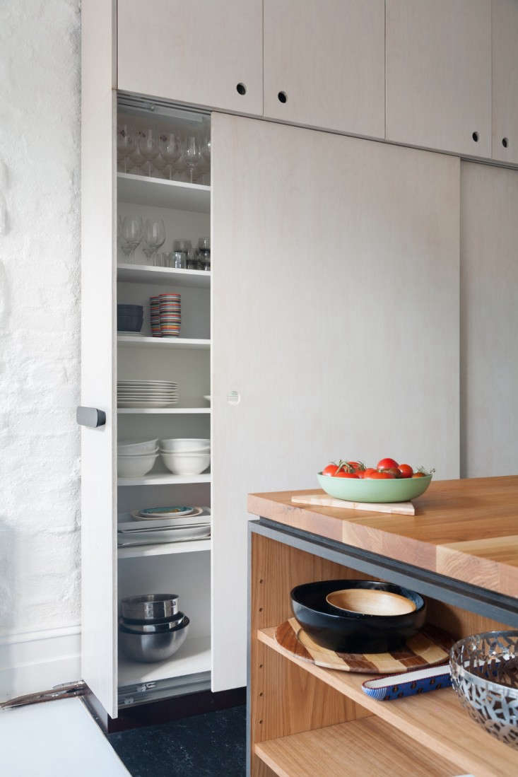 Having sliding doors on a wall of ceiling-high cabinets allows the homeowners to walk through this narrow passageway unimpeded.