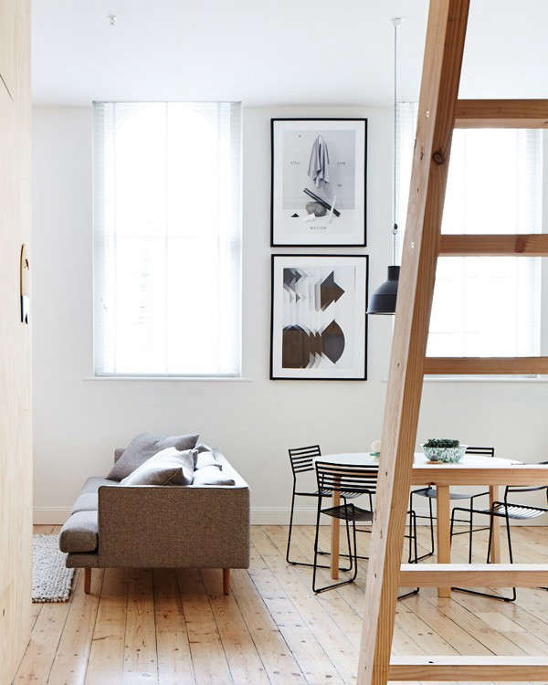 While only 800 square feet, the studio apartment–viewed here from the entry–has tall ceilings and windows on three of its four walls which contribute to the bright, expansive feel of the space. The ladder leads to a storage loft.