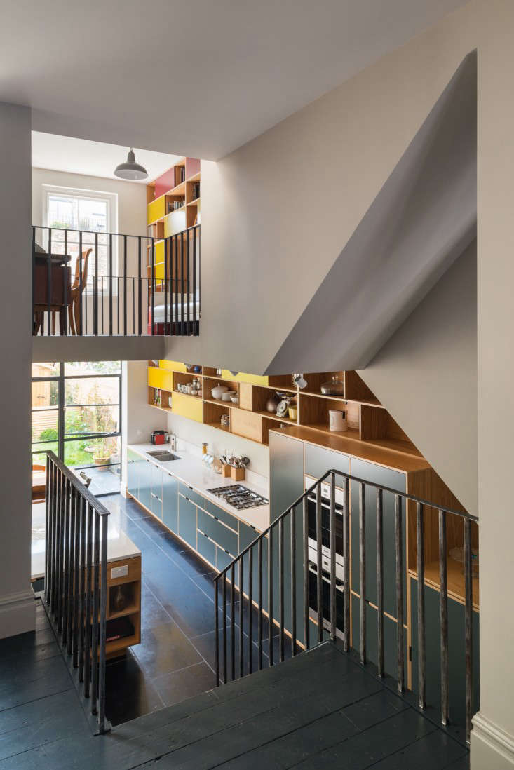 Stairs off the living room lead down to the large kitchen and dining area, which has been opened up in the front and back to the study. The steel banister echoes the lines of the balcony above and the new screen of steel-frame glazing below.