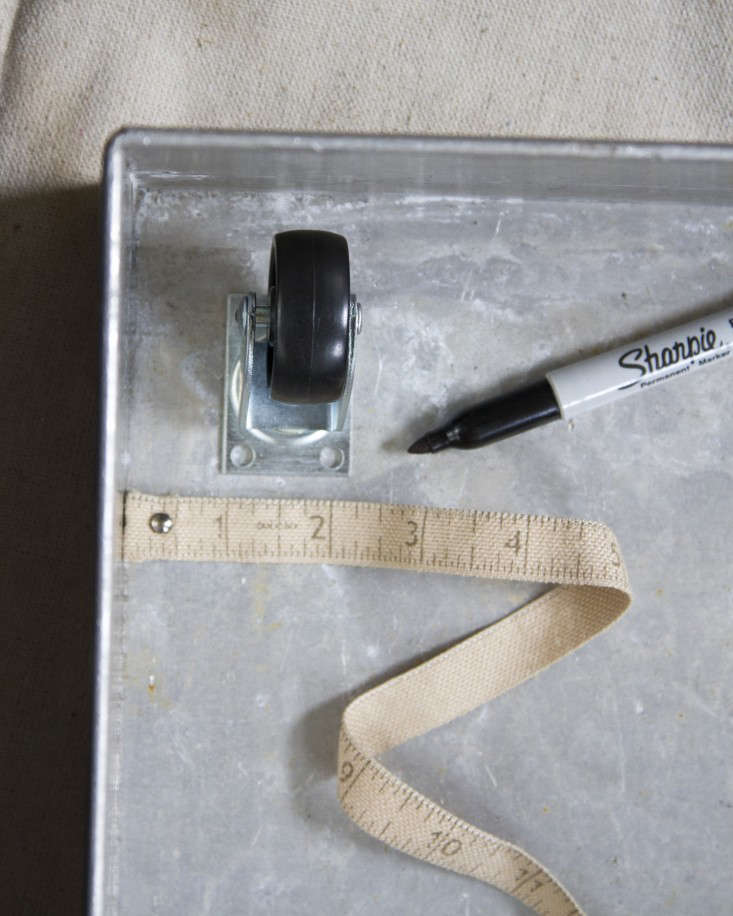 To begin, I marked dots on a metal box to indicate where four casters would sit. (I measured an inch in from the box’s edges so the wheels would stay beneath the tray even when swiveled.)