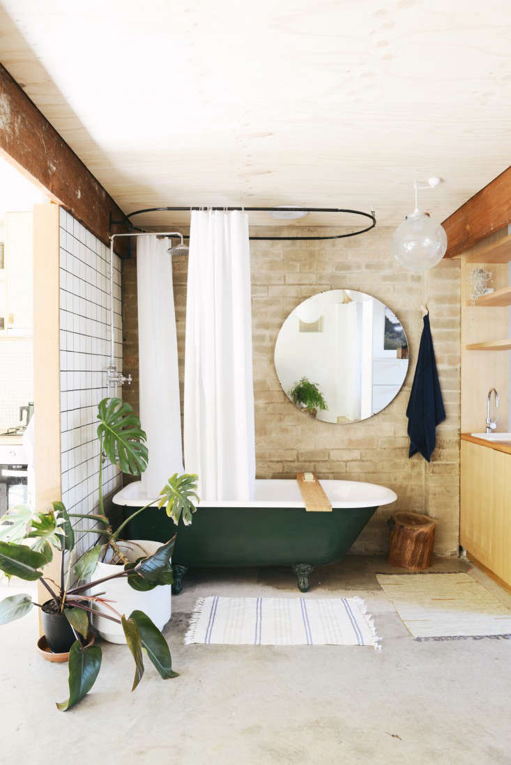 A salvaged clawfoot tub takes center stage in the bathroom area (not to be outdone by the impressive splitleaf philodendron). A large mirror helps brighten the apartment and give a sense of expanded space.