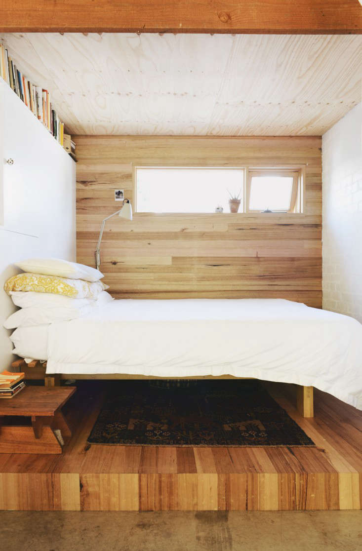 Built onto a raised platform of salvaged wood, a simple bed. The architects took care to reposition windows to provide premium views of the neighboring gum trees, while also maintaining privacy for the homeowners.