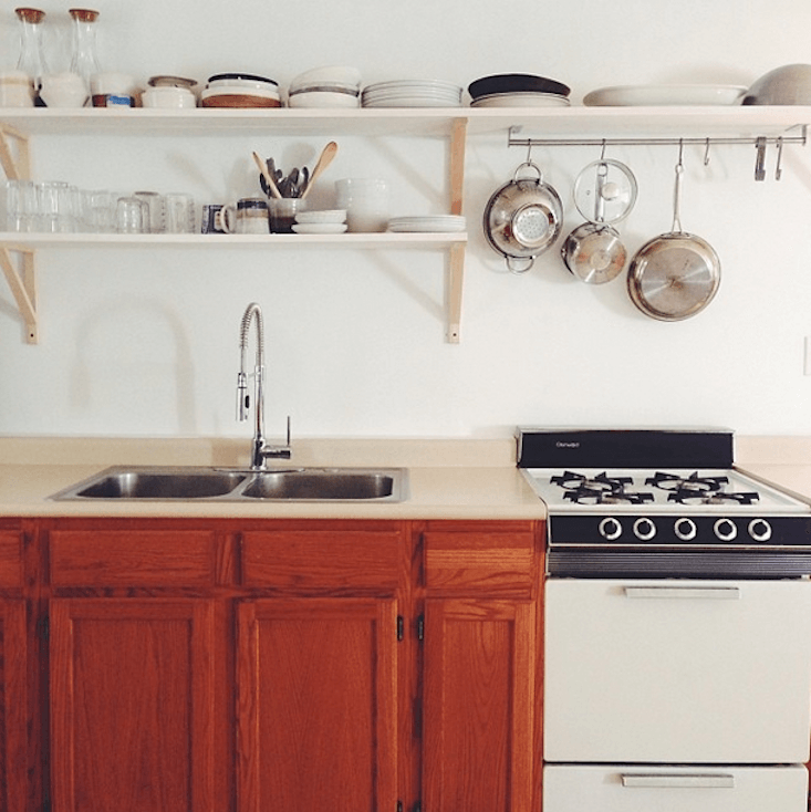 The cabinets awaiting paint. Here’s Suzie’s description of the open-shelf prep: “First we measured the length and depth we wanted. We decided to run two six-inch-deep boards across our brackets to have an approximate shelf depth of twelve inches. We knew we wanted to run one shelf along the whole length of the wall and have a shorter one running over the sink but not over the stove, so we took our measurements accordingly.”