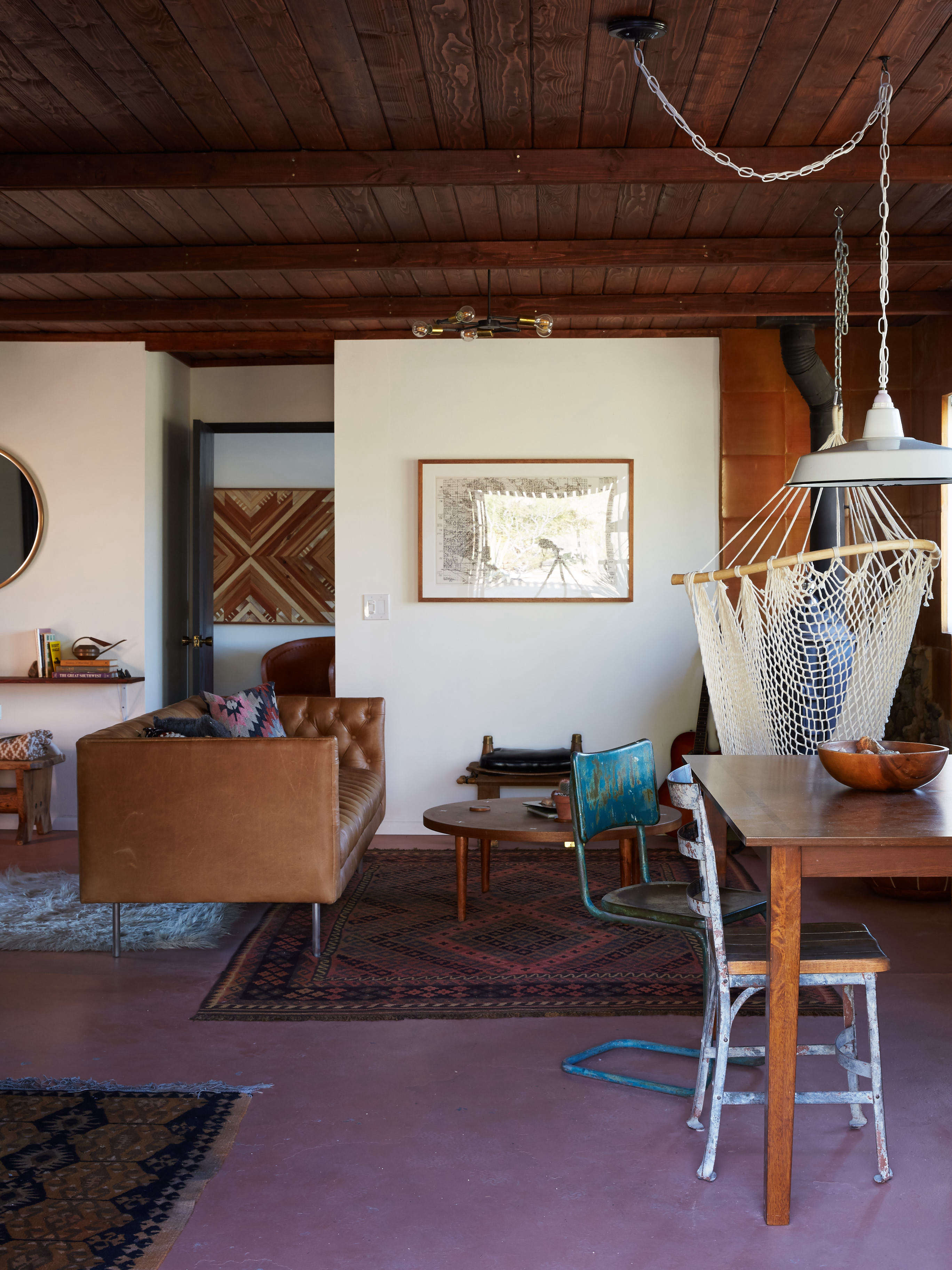 joshua tree casita airbnb living room in desert colors with hanging swing and painted concrete floor, kate sears photo