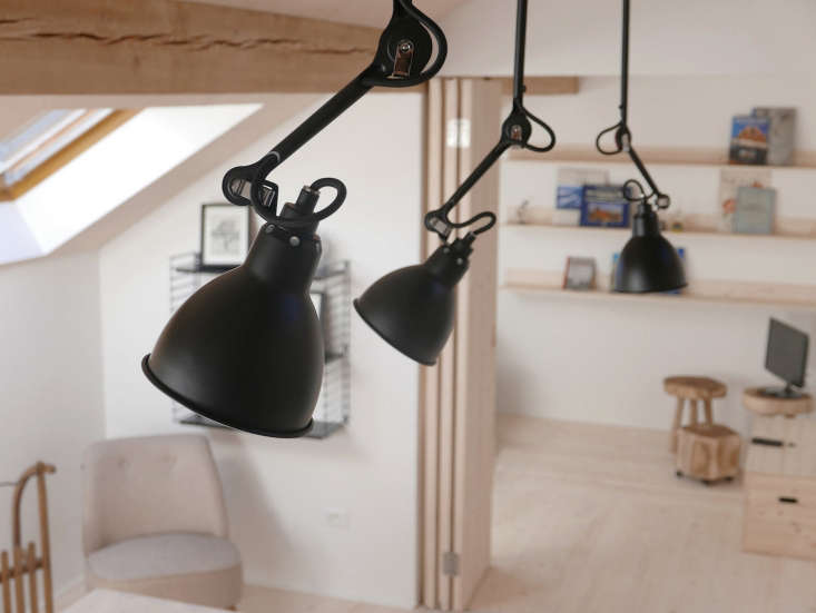 Three matte black Lampe Gras ceiling lights—a favorite of architect Le Corbusier—hang above the dining table.