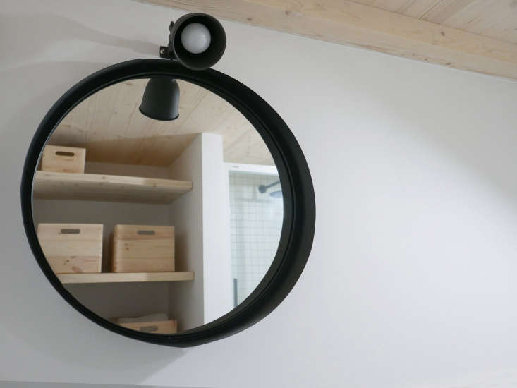  The materials palette extends to the bathroom, with a matte black metal mirror and pine open shelving.