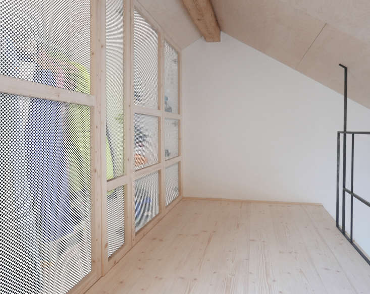 A perforated white screen obscures clothes storage in the lofted sleeping space.