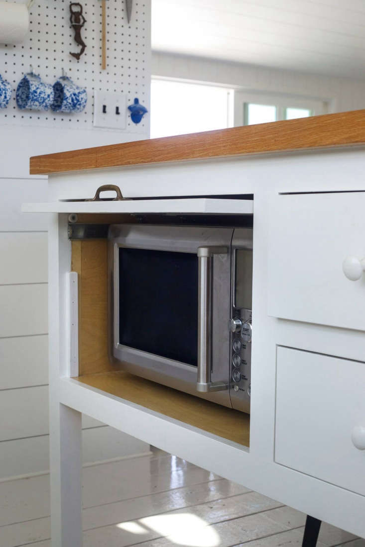 The Breville Quick Touch Microwave ($249.95 at Williams-Sonoma) is concealed in the kitchen island with a retractable door. For more countertop microwaves to stow away, see our post 10 Easy Pieces: Countertop Microwaves. The floors throughout the house are painted in a California Paint high-gloss finish.