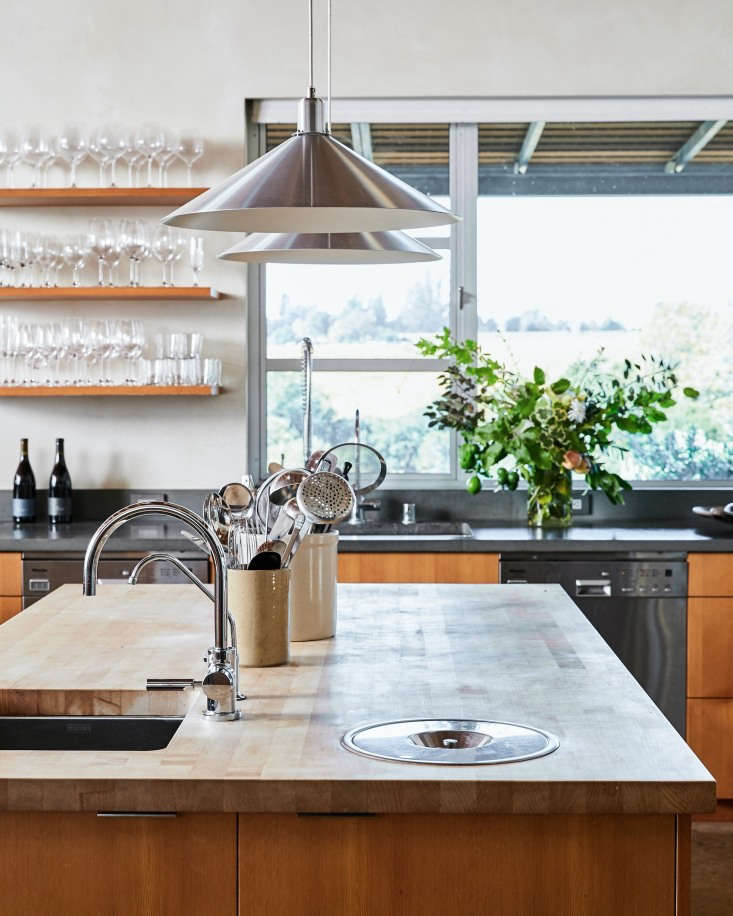 A large central island in the Sebastopol kitchen of winemaker Stephen Singer and his partner Michel Boynton, proprietors of Baker Lane Vineyards, features a butcher block countertop and integrated sink and compost pail. Photograph by Daniel Dent for Remodelista, from Kitchen of the Week: Part Tasting Room, Part Home Kitchen at Baker Lane Vineyards in Sonoma.