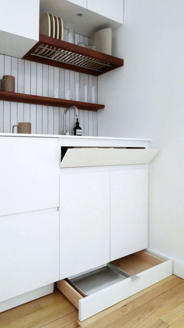 The cabinet fronts are flat MDF panels with a sprayed, white lacquer finish. The toe kick drawers have stainless steel edge pulls (“because they are basically invisible”), and the cabinets have recessed bevels that serve as pulls.