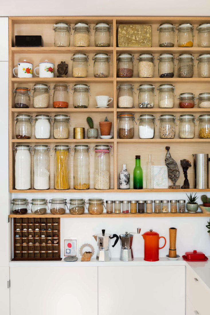 Wood pantry open shelving with decanted jars in a London apartment kitchen 