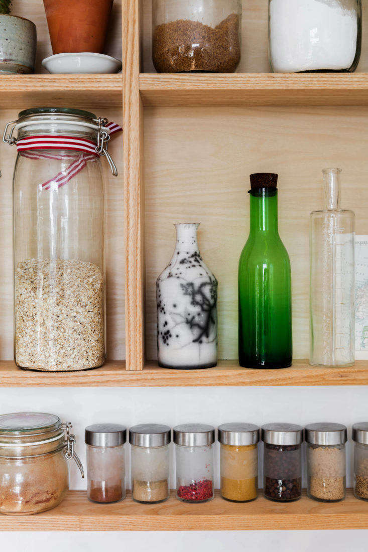 Wood pantry open shelving with decanted jars in a London apartment kitchen 