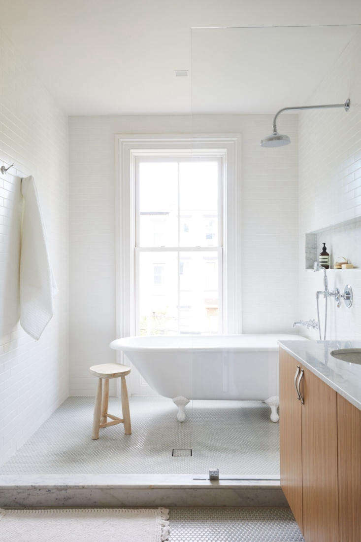  A wet room with tub and shower enclosed behind a glass partition features a long niched shelf. Photograph by Nicole Franzen, from Rehab Diary: Monochromatic Luxe in Park Slope.